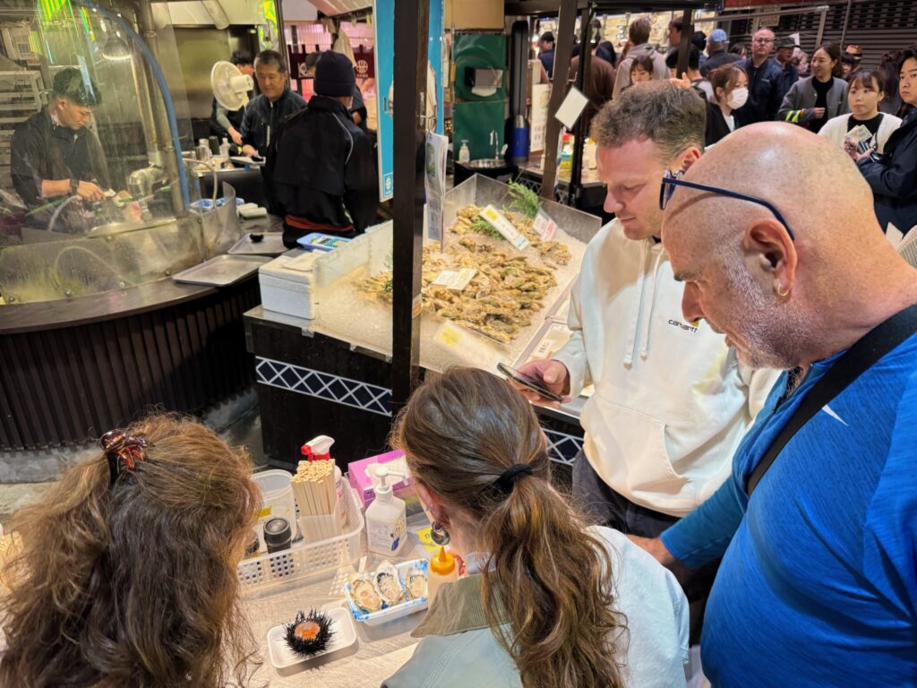 Visitors exploring fresh seafood stalls at Omicho Market during a Kanazawa walking tour, guided by local experts.