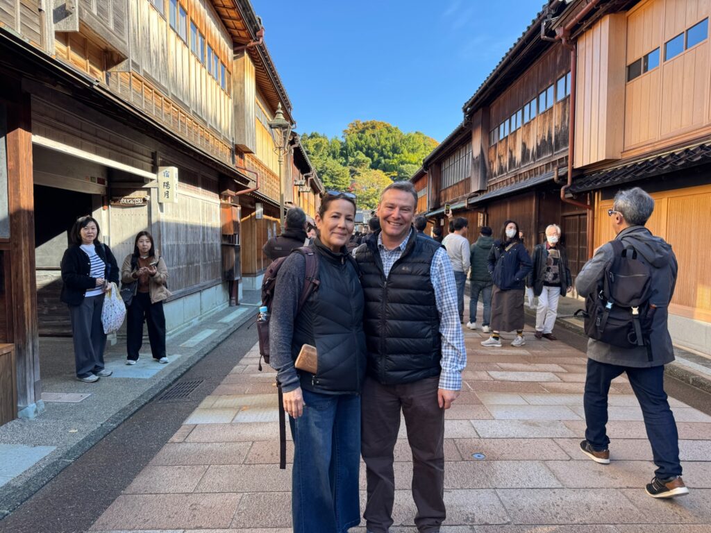 Tour guests standing in Kanazawa’s Higashi Chaya District during a walking tour, with traditional wooden teahouses in the background.