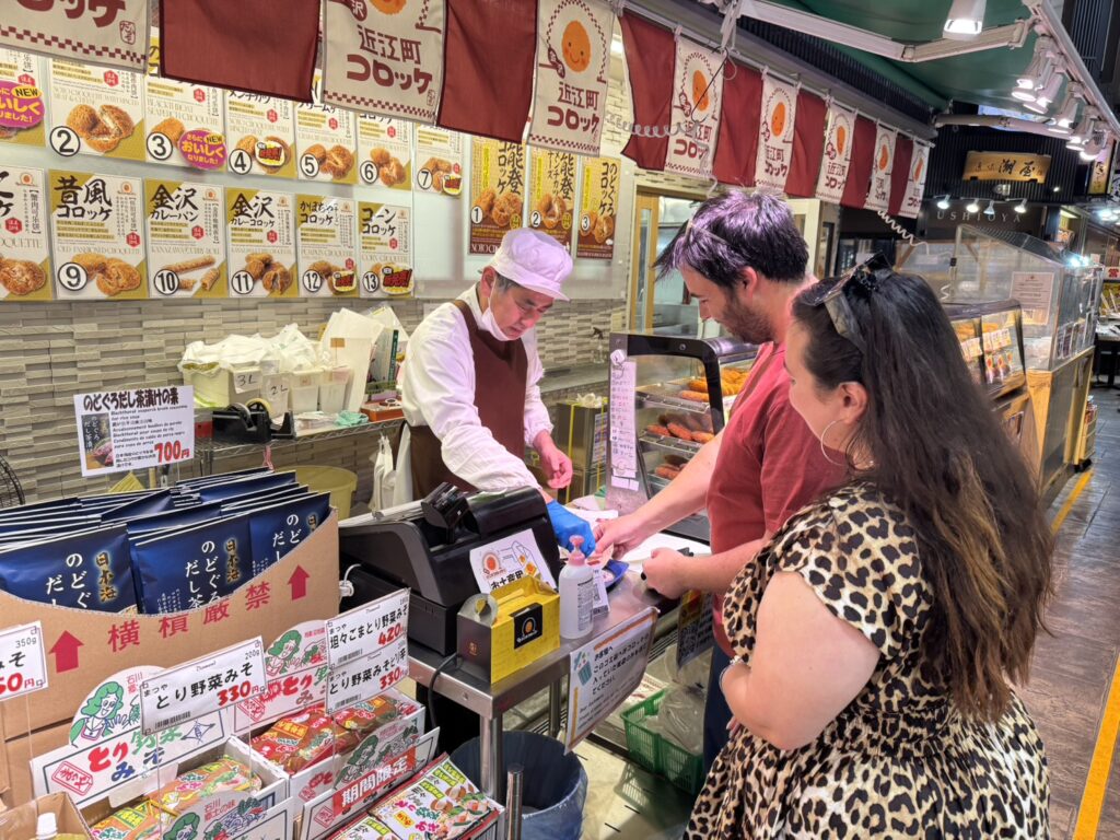 Kanazawa walking tour at Omicho Market with a local guide and guests enjoying seafood