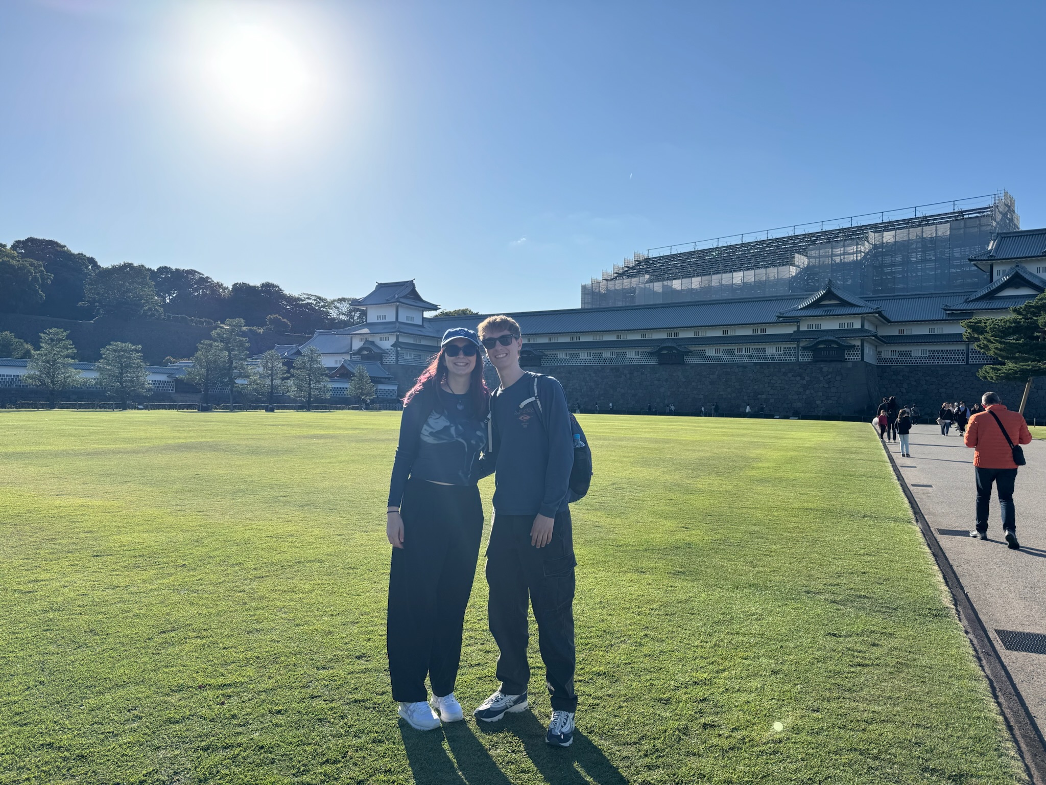 Two travelers standing in front of Kanazawa Castle on a sunny day during the walking tour
