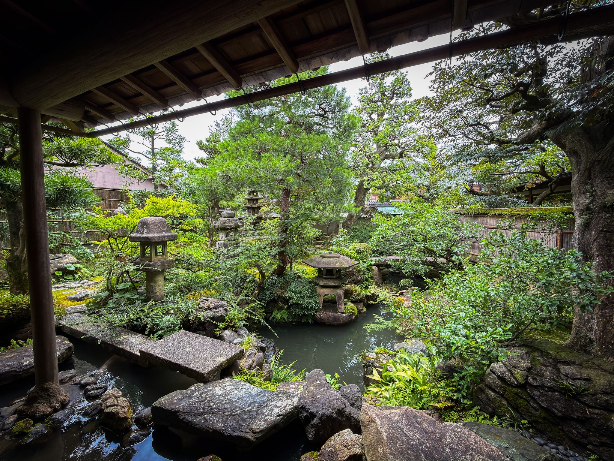 Traditional Japanese garden with stone lanterns and greenery viewed from a residence in Kanazawa